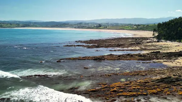 Berrak suların ve yemyeşil tepelerin yanında çarpıcı kayalık bir kıyı şeridi gösteren nefes kesici bir manzara.