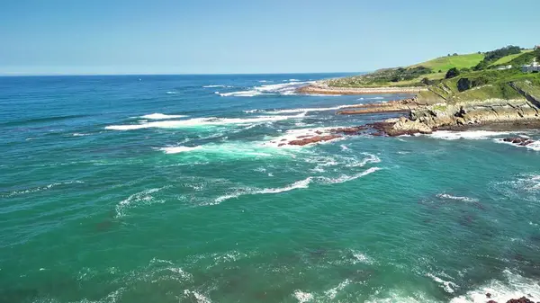 Çarpıcı insansız hava aracı görüntüleri canlı mavi suları ve engebeli kayalık kıyıları olan güzel bir kıyı şeridi gösteriyor.