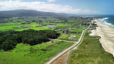 Kıyı şeridindeki yemyeşil tarlaların büyüleyici hava manzarasının tadını çıkarın, karanın ve denizin güzelliğini vurgulayın.