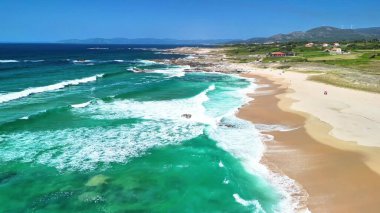 Açık mavi gökyüzünün altında kumlu bir sahile çarpan dalgaların çarpıcı hava manzarasını tecrübe etmek, doğanın güzelliğini gözler önüne sermek.