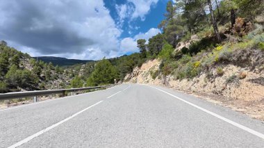 Güzel ve dolambaçlı bir dağ yolu keşfedin, dinamik, renkli bir gökyüzünün altında yemyeşil bir alanda dolambaçlı