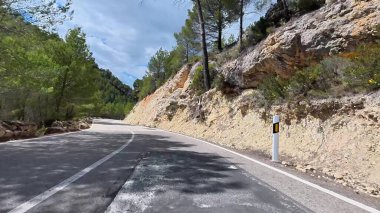 Güzel ve büyüleyici bir yol yemyeşil ağaçlar ve çarpıcı kayalık yamaçlarla çevrili.