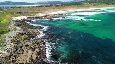 Güzel bir hava görüntüsü kayalık bir kıyı ve canlı turkuaz suların kumlu sahillerle buluşmasını gösteriyor..
