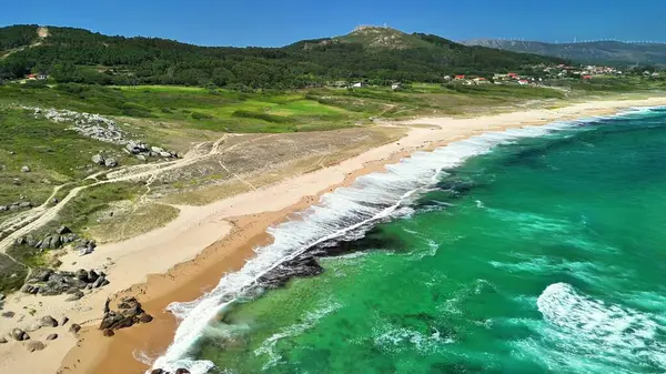 Göz kamaştırıcı bir hava görüntüsü, berrak turkuaz sular ve bereketli manzaralarla süslenmiş sakin bir sahili güzel bir şekilde resmediyor.