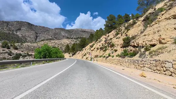 Çarpıcı bir manzara dağların arasından mavi bir gökyüzünün altında, keşif ve macera için ideal bir yol gösteriyor.