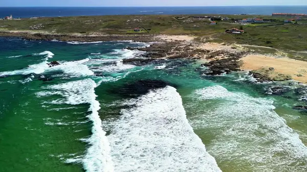 Canlı bir sahil sahnesinin nefes kesen görüntüsü dalgalarla sarmalanmış kayalık kıyıları sergiliyor.