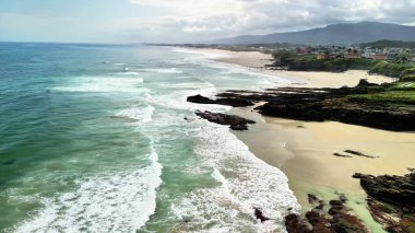 Nefes kesici bir hava manzarası, dalgaların engebeli kayalık kıyılara nazikçe çarptığı sakin bir sahili gözler önüne seriyor.