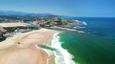 Temiz suları ve yemyeşil tepeleri olan güzel bir sahil manzarasını gösteren nefes kesici bir hava görüntüsü..