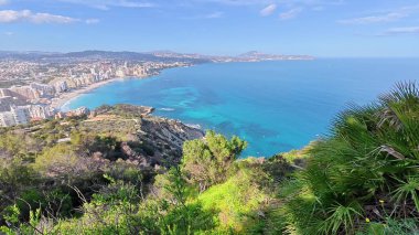Güneşli, mavi gökyüzünün altında nefes kesici kıyı şeridi ve kristal berrak suların nefes kesici manzarasını tecrübe edin.