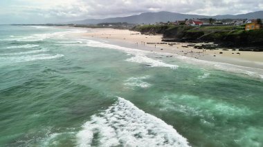 Hava manzarası, berrak mavi suları ve altın plajları olan sakin bir kıyı şeridini gösteriyor. Rahatlamak için ideal.