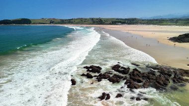 Dalgaları ve güneşten hoşlanan insanları gösteren canlı, renkli bir plajın kesinlikle nefes kesici bir görüntüsü.