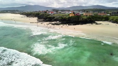 Temiz suları ve kıyı boyunca renkli evleri olan sakin bir plajın nefes kesici manzarasının tadını çıkarın.