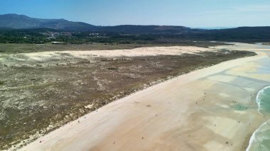 Sakin bir plajın nefes kesici hava manzarası, güzel kumlu kıyıları ve berrak mavi suları aydınlatıyor.