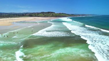 İnanılmaz berrak suları ve dalgalı dalgalarıyla nefes kesici bir sahili gösteren hava manzarası.