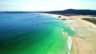 Nefes kesici bir hava manzarası berrak, güneşli bir gökyüzünün altında nefes kesici turkuaz sularla sakin bir sahili yakalar.