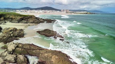 Nefes kesen bir sahil manzarası uzak bir yerde kayalık kıyılara çarpan güçlü dalgaları gösteriyor.