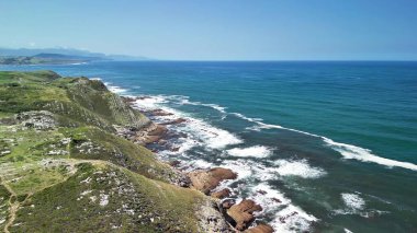 Açık mavi okyanus dalgalarıyla birlikte çarpıcı kayalık kıyı şeridini gösteren nefes kesici hava görüntülerinin tadını çıkarın.