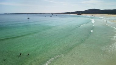 Güzel, sakin bir sahil sahnesi berrak, davetkar sular, nazik dalgalar ve büyüleyici bir sahil şeridi.