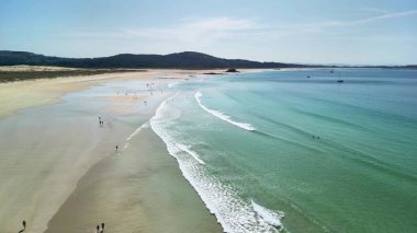 Gerçekten çarpıcı bir sahil sahnesi kristal berrak sular, yumuşak dalgalar ve güneşten zevk alan birçok ziyaretçinin yer aldığı.