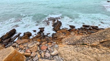 Huzurlu ve huzurlu bir sahil sahnesi. Kayalık bir kıyı şeridi ve yanında hafif dalgalar.