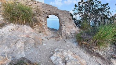 Nefes kesen bir kıyı kaya oluşumu güzel bir şekilde okyanusun huzurlu ve huzurlu manzarasını çerçeveliyor.