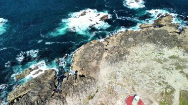 Nefes kesici hava çekimi kayalık kıyı şeridi ve çarpan dalgaların yanında canlı turkuaz sular..