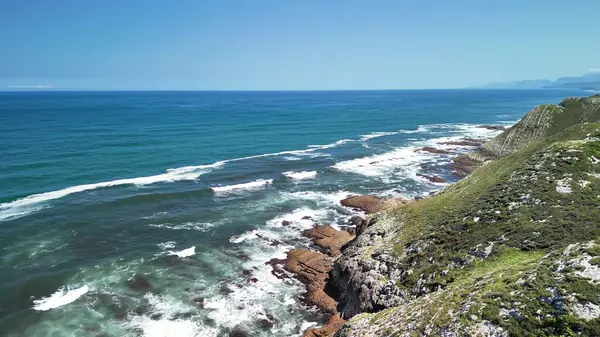 Çarpıcı deniz manzarası dalgaların engebeli kayalıklara çarptığını gösteriyor.