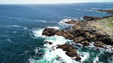 Nefes kesici hava manzaraları çarpıcı mavi okyanus dalgalarının çarptığı çarpıcı kayalık bir kıyı şeridini gösteriyor.