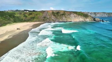 Turkuaz suları ve berrak gökyüzünün altındaki etkileyici uçurumlarla çarpıcı bir kıyı manzarası.