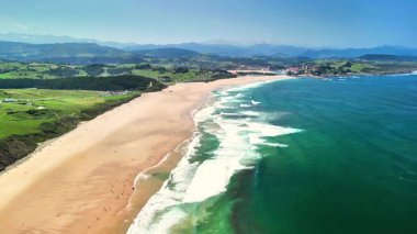 Nefes kesici bir kıyı manzarası çarpıcı bir kumsal ve dalgalı dalgalar altında berrak ve parlak mavi bir gökyüzü