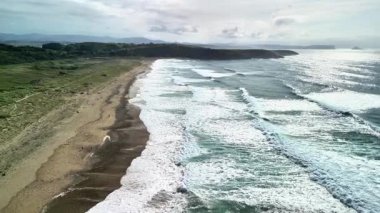 Nefes kesici bir hava manzarası çarpıcı dalgalar ve canlı kıyı manzaralarıyla nefes kesici sakin bir plajı gösteriyor.