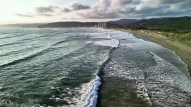 İnanılmaz güzellikteki gün batımında okyanus dalgalarının yavaşça kıyıya vuruşunu hissedin.