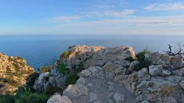 Göz kamaştırıcı, nefes kesici panoramik manzara görkemli kayalık uçurumlar ve parlak bir gökyüzünün altında sakin bir okyanus.