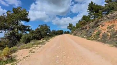 Büyüleyici bir toprak yolun tadını çıkar, bereketli ağaçların ve kabarık bulutların arasında gezinerek büyüleyici bir manzarayı keşfetmeye davet et.