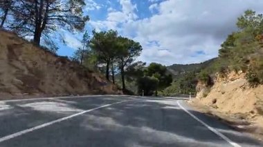 Bereketli ağaçlar ve göz kamaştırıcı manzaralarla çevrili dolambaçlı bir dağ yolu var.