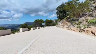 Bereketli yeşillik ve canlı gökyüzü ile çevrili pitoresk bir dağ yolu, seyahat görüntüleri için mükemmel..