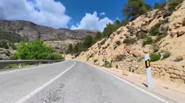 Çarpıcı bir manzara dağların arasından mavi bir gökyüzünün altında, keşif ve macera için ideal bir yol gösteriyor.