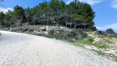 Güzel, resimsi çakıllı bir yol yemyeşil manzaralar ve açık mavi gökyüzü arasında yavaşça dönüyor.