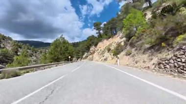 Güzel ve dolambaçlı bir dağ yolu keşfedin, dinamik, renkli bir gökyüzünün altında yemyeşil bir alanda dolambaçlı