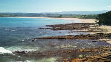 Berrak suların ve yemyeşil tepelerin yanında çarpıcı kayalık bir kıyı şeridi gösteren nefes kesici bir manzara.
