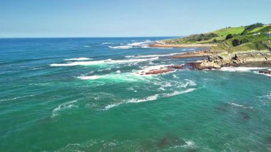 Çarpıcı insansız hava aracı görüntüleri canlı mavi suları ve engebeli kayalık kıyıları olan güzel bir kıyı şeridi gösteriyor.