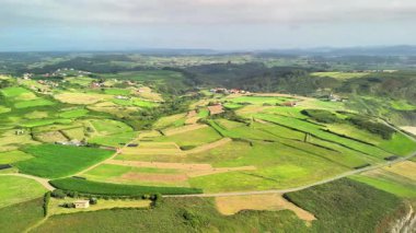 Canlı yeşil tarlaları ve manzarayı saran tepeleri güzel gösteren nefes kesici bir manzara.