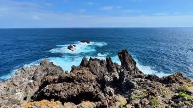 Göz kamaştırıcı okyanus manzaraları, parlak mavi gökyüzünün altındaki canlı dalgalarla birlikte kayalık kayalıkları çok güzel gösteriyor.