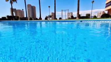 Havuzun berrak mavi suyu, parlak güneş ışığını yansıtırken parıldıyor, herkesi rahatlatıyor ve eğlendiriyor.