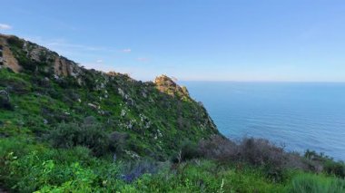 Parlak yeşillik ve berrak bir gökyüzünün altındaki dingin mavi okyanusla nefes kesici kıyı manzarasını deneyin.