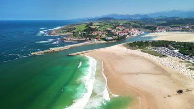Sersemletici hava görüntüsü sakin suları ve arka planda yeşil tepeler olan güzel kumlu kıyıları yakalıyor..