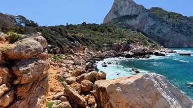 Parlak mavi gökyüzünün altındaki masmavi denizin yanı sıra kayalık kıyı şeridinin nefes kesici ve çarpıcı manzarasını tecrübe edin.