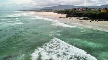 Hava manzarası, berrak mavi suları ve altın plajları olan sakin bir kıyı şeridini gösteriyor. Rahatlamak için ideal.