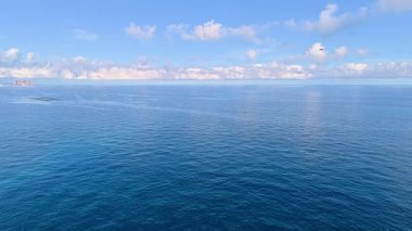 Okyanus ufku, mavi gökyüzünün altında durgun sularla uzanıyor. Rahatlamak ve ilham vermek için mükemmel.