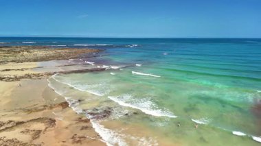 Güzel ve sakin bir sahil manzarası kristal berrak sular ve güneşli bir gökyüzünün altında canlı bir kıyı şeridi.